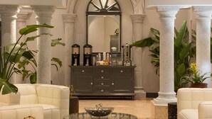 A lobby with a marble columned archway, a dark wood cabinet with various items, and white leather sofas. - Lexington by Hotel RL Miami Beach (Miami Beach)