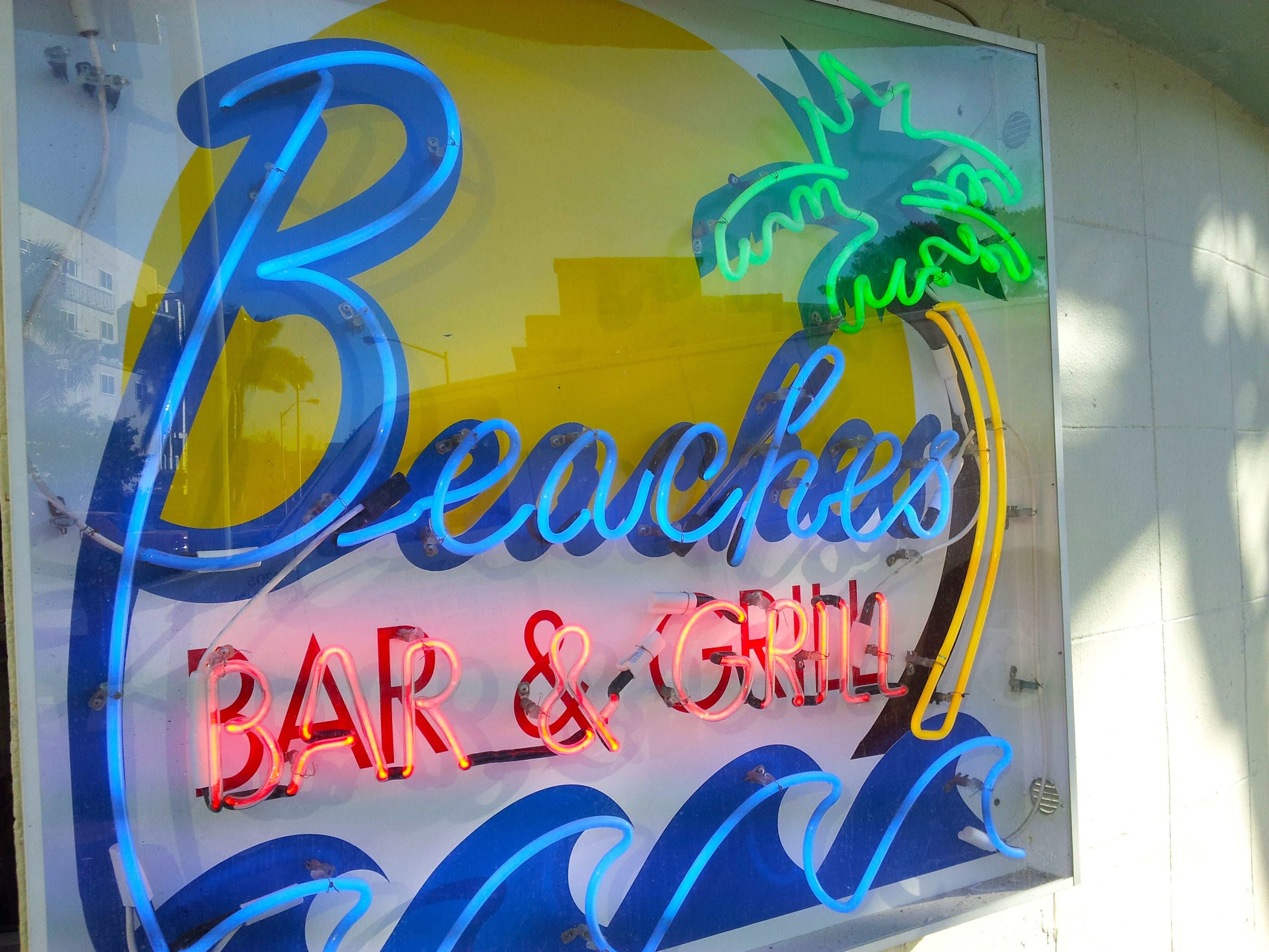 Un letrero de neón para un bar y parrilla con temática playera.