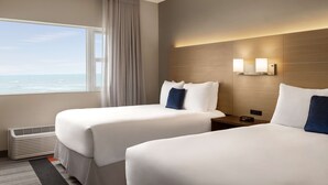 A hotel room with two beds, a large window with a view of the ocean, a wall-mounted light fixture, and a heater. - Lexington by Hotel RL Miami Beach (Miami Beach)