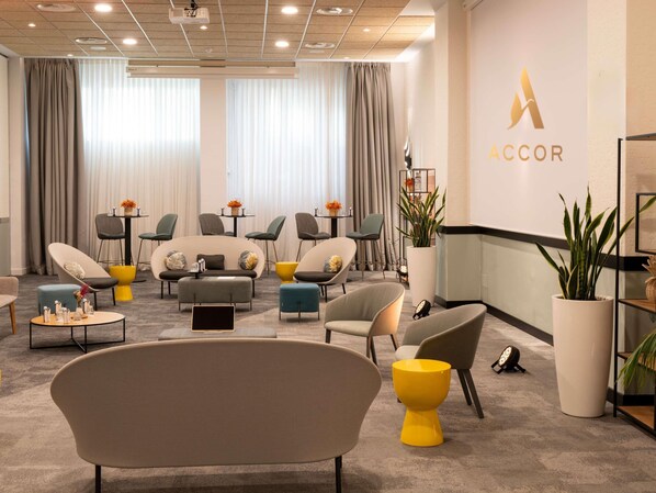 A modern hotel lobby with a neutral color palette, comfortable seating, a large plant, and a prominent ACCOR logo. - Novotel Madrid Feria and Airport (Madrid)