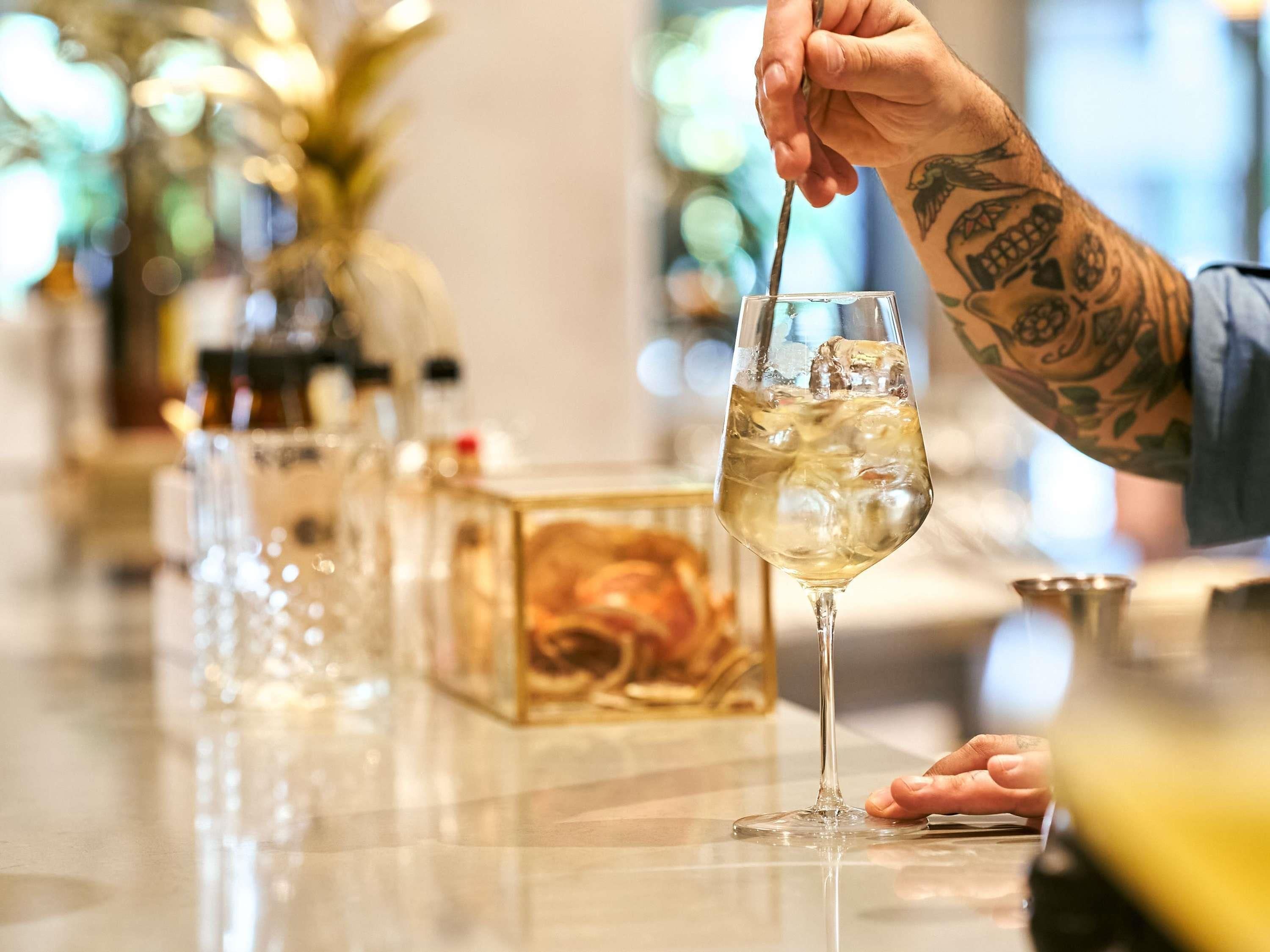 A bar setting with a glass of white wine, bottles, and a decorative box.