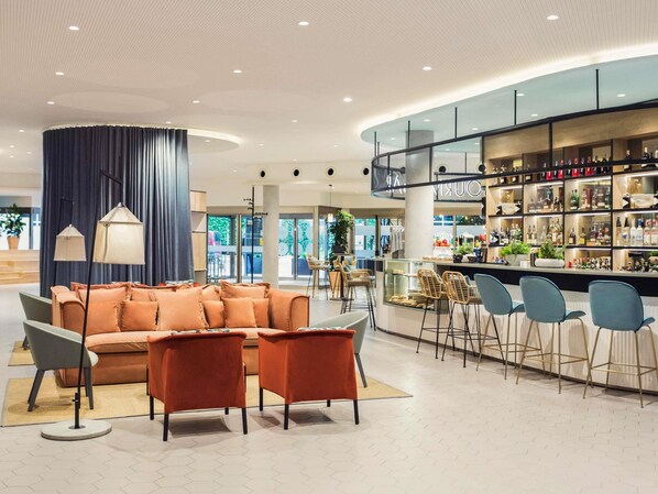 Un intérieur moderne avec un bar, des espaces pour s’asseoir et une vue sur l’extérieur.