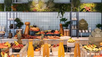 Un buffet con una vasta scelta di cibi e bevande, tra cui frutta, formaggi e dolci.