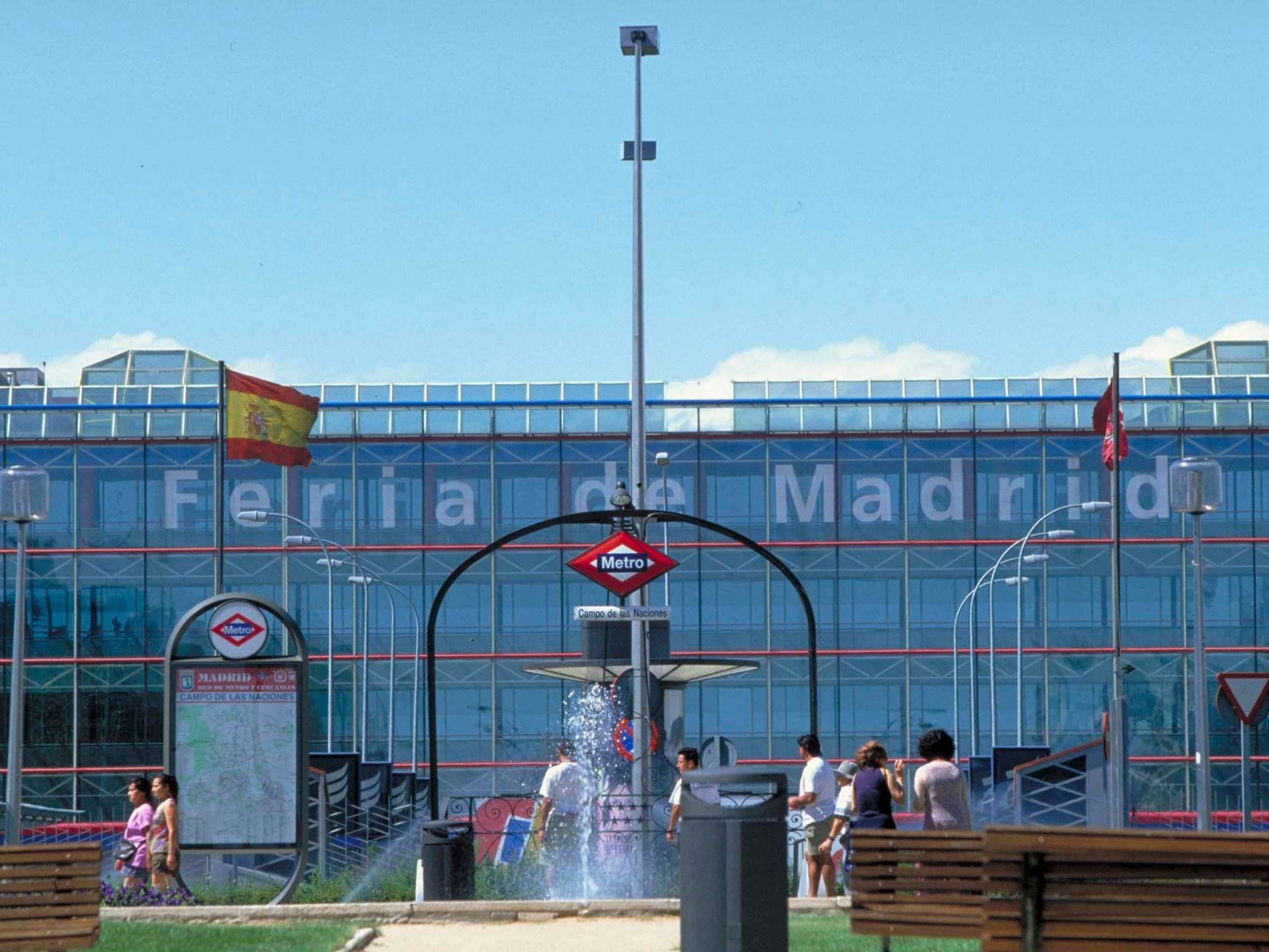Un bâtiment moderne avec une façade en verre, une fontaine et un panneau indiquant l’entrée du métro.