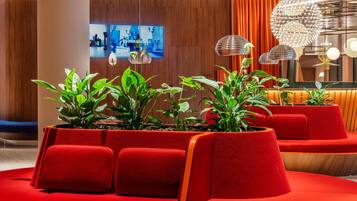 Un vestíbulo moderno con asientos rojos, plantas en macetas e iluminación contemporánea.