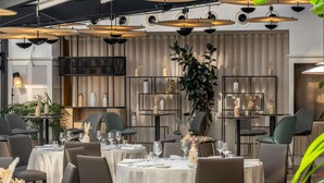 Un restaurante con mesas redondas, sillas grises e iluminación colgante.