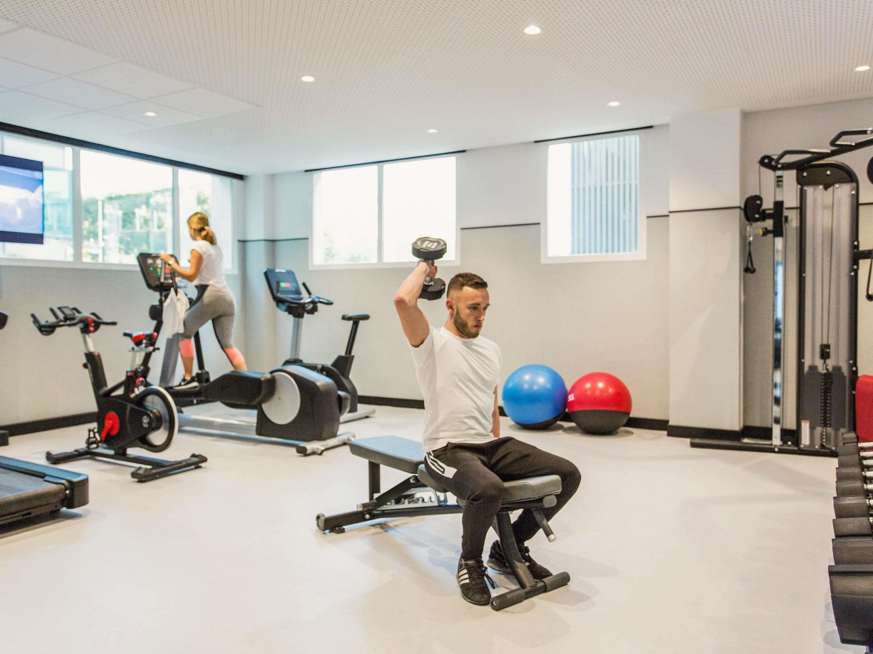 A gym with exercise equipment, a treadmill, and a seated dumbbell workout area.
