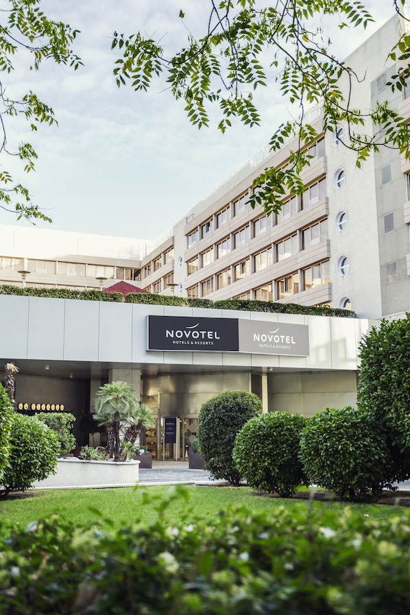 A modern hotel building with a sign reading "NOVOTEL HOTELS & RESORTS."