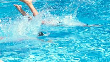 Una piscina al aire libre de temporada, sombrillas