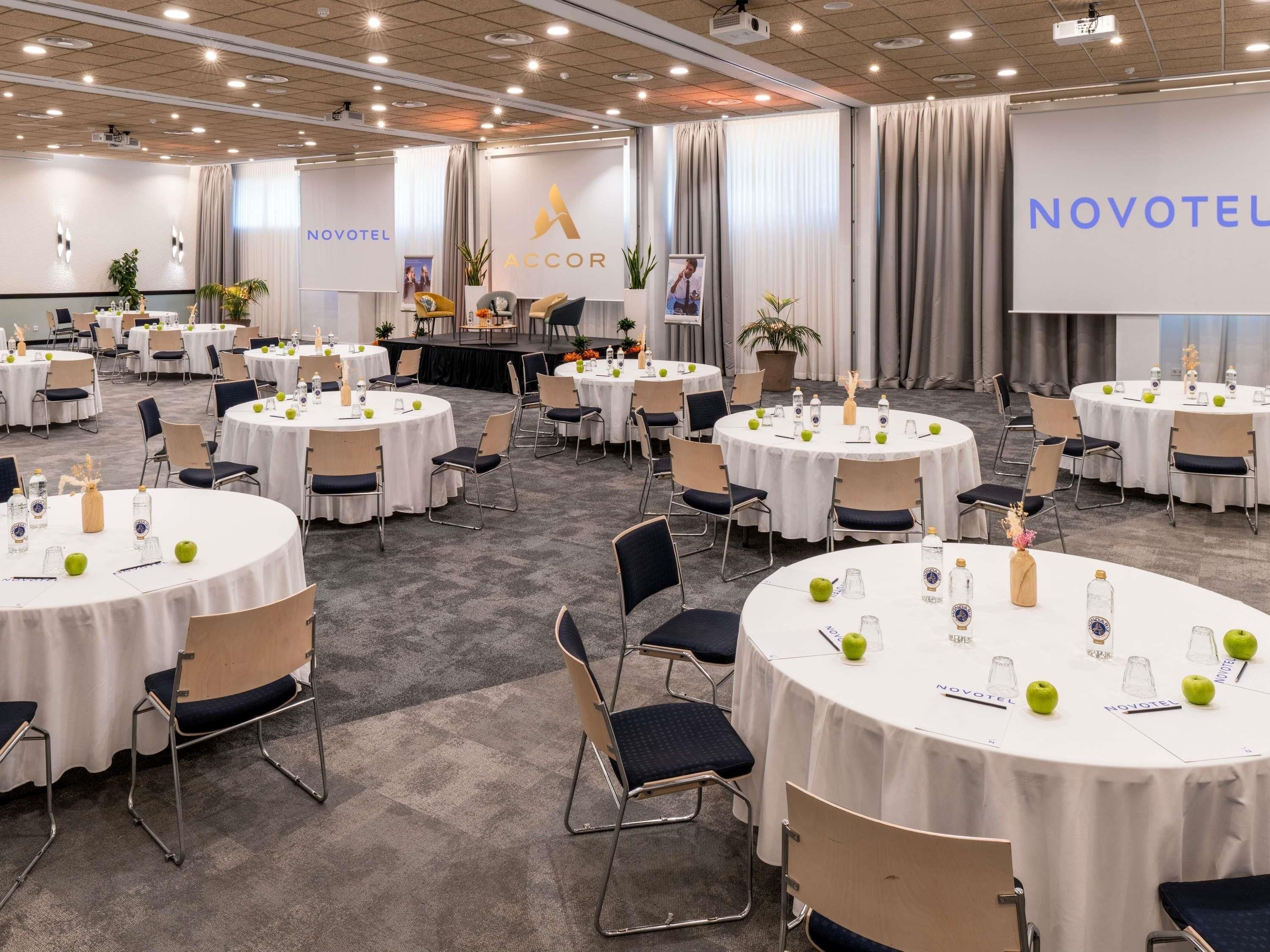 A conference room with round tables, chairs, and a stage.