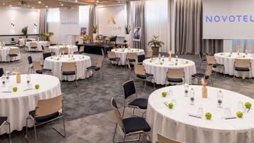 A conference room with round tables, chairs, and a stage.
