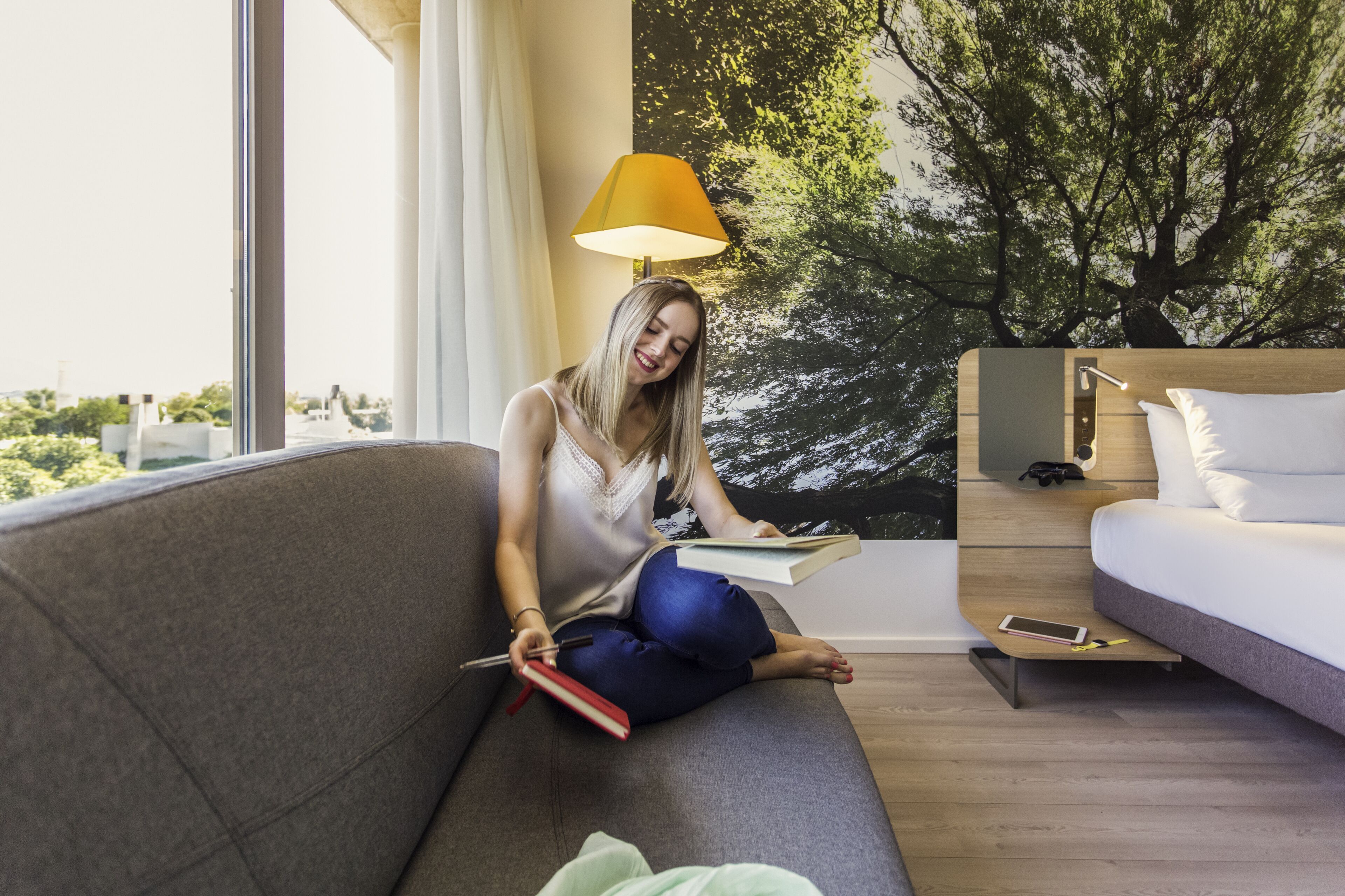 Una sala de estar moderna con un sofá, una lámpara de lectura y un ventanal grande.