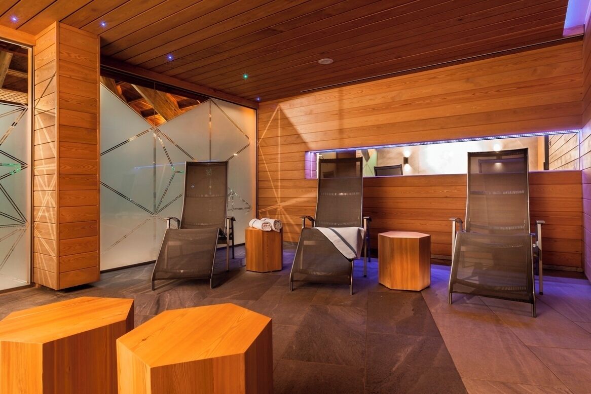 Un moderno espacio de spa con paneles de madera, separaciones de vidrio y zonas de estar.