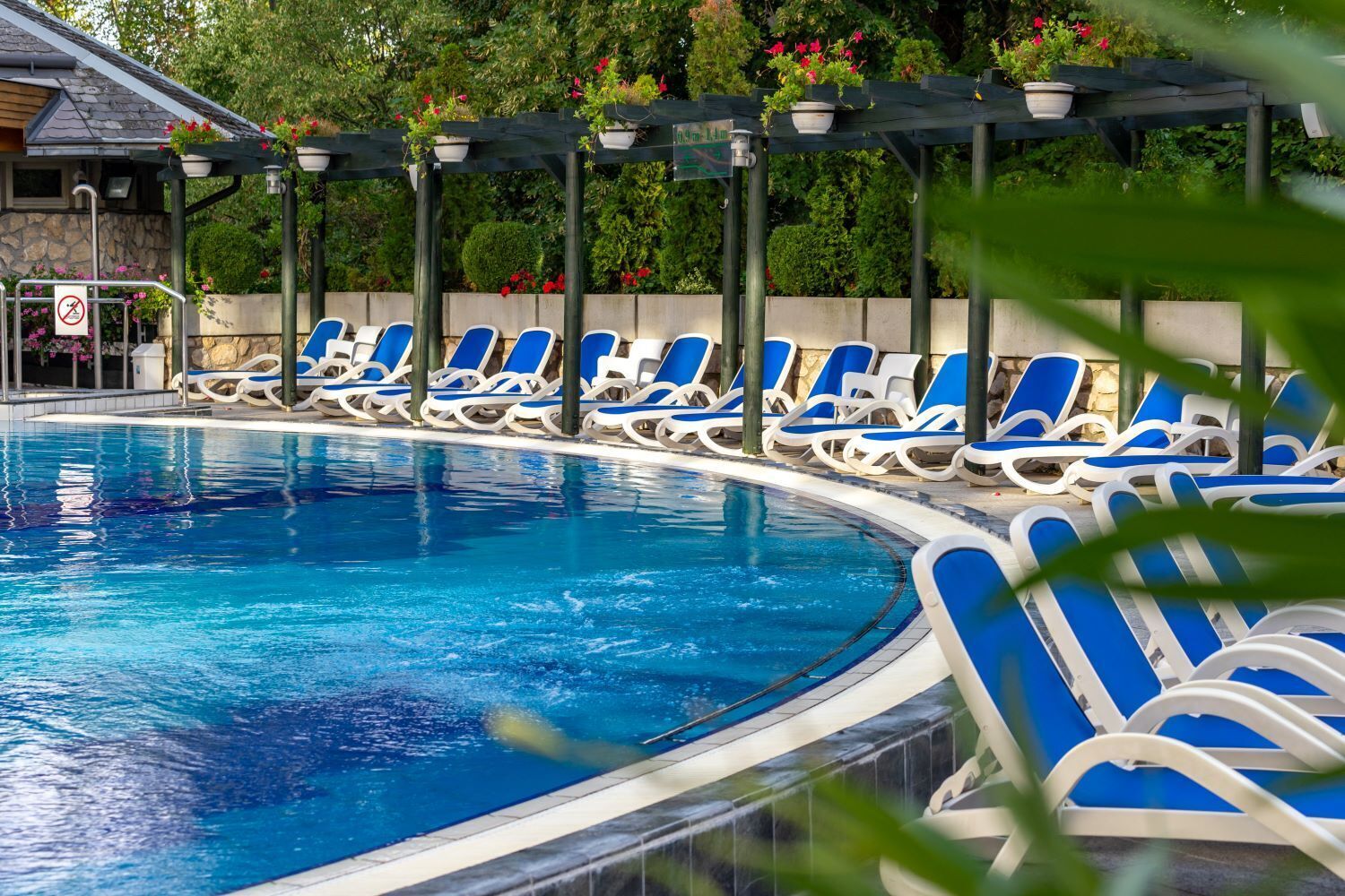 A swimming pool with blue and white lounge chairs arranged around it.