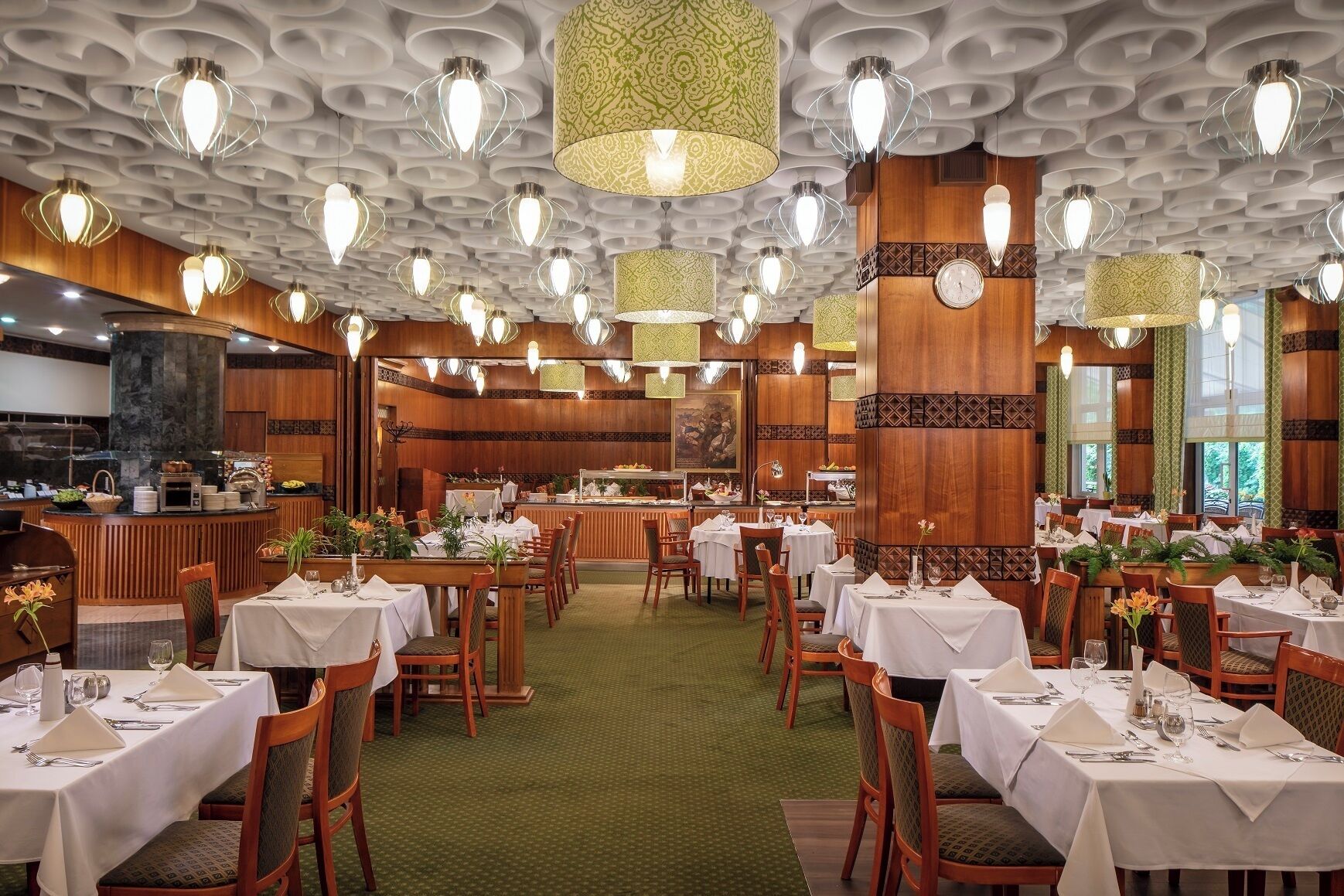 Un restaurant avec des tables rondes, des chaises et des lampes suspendues.