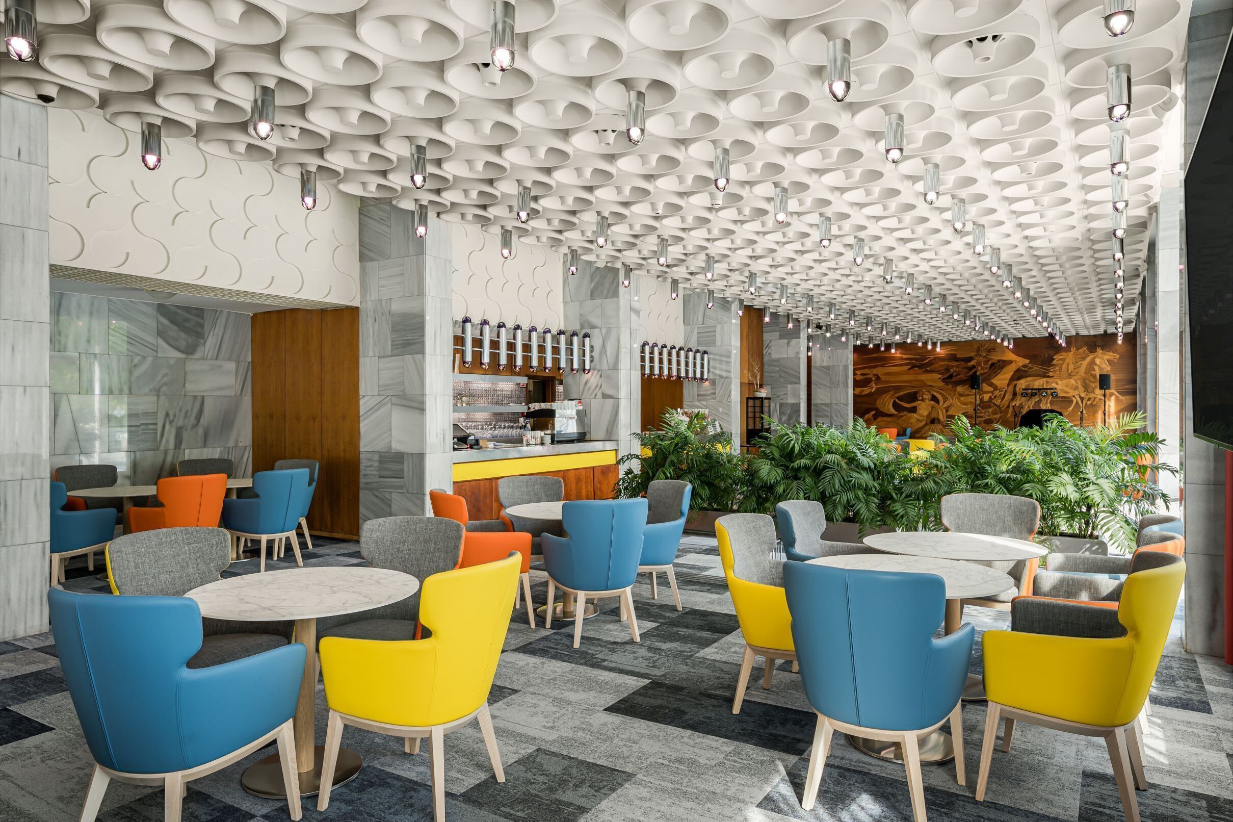 Un interior moderno con un diseño de techo único, una zona de bar y asientos coloridos.