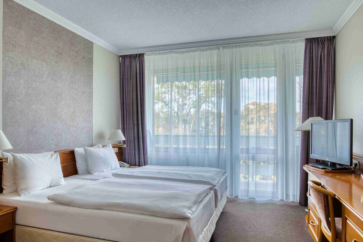A hotel room with two beds, a television, and a desk.