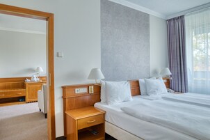 Habitación de hotel con una cama grande, dos mesitas de noche con lámparas, un escritorio de madera y un espejo.