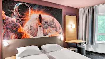 A hotel room with a large space-themed artwork on the wall, a bed with white linens, a bedside table, a nightstand, and a window with curtains.