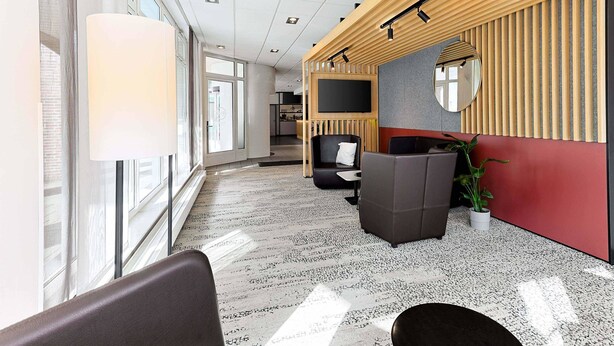 A modern office space with a reception area, seating, and a large flat-screen TV.