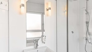 A modern bathroom with a glass-enclosed shower, a white sink, and two wall-mounted lights.