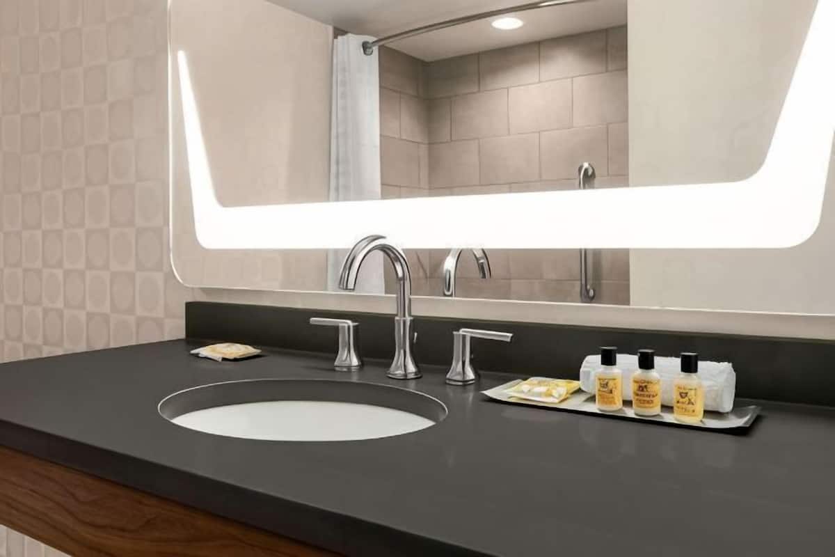 Een moderne badkamer met een grote spiegel, een wastafel en toiletartikelen.