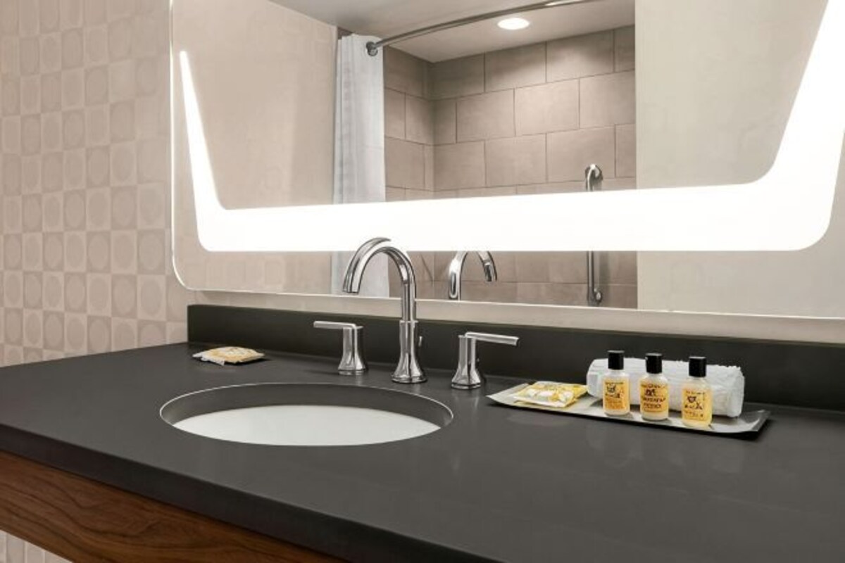 Un baño moderno con un espejo grande, un lavabo y artículos de aseo.