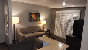 A hotel room with a sofa, two bedside tables with lamps, a TV, a painting on the wall, and a large closet. - Best Western Corvallis (Corvallis)