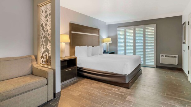 A hotel room with a bed, bedside tables, a sofa, a decorative wall panel, and a window with blinds. - Best Western Corvallis (Corvallis)