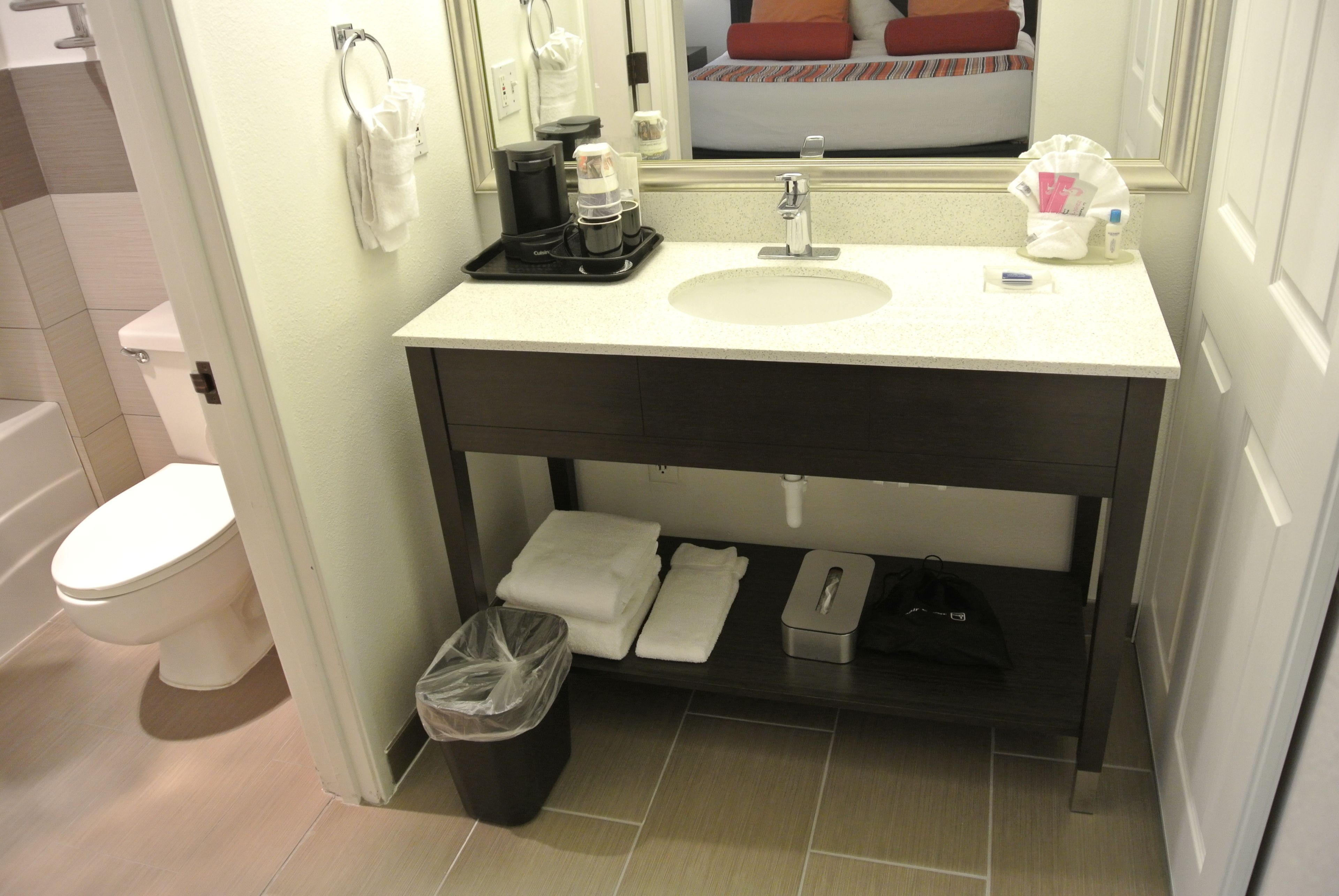 Un baño con lavamanos, inodoro y un cubo de basura.