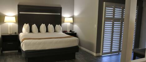 Una camera da letto con un letto grande, due comodini con lampade, una testiera scura e un armadio con ante scorrevoli.