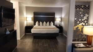 A modern hotel room with a large bed, two bedside tables with lamps, a flat-screen TV, and a decorative wall panel. - Best Western Corvallis (Corvallis)