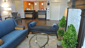 A hotel lobby with a blue sofa, a patterned armchair, a small round table, and a reception desk. - Best Western Corvallis (Corvallis)