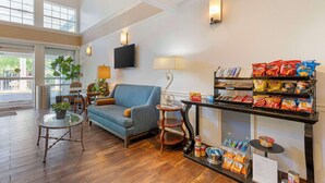 A spacious lobby with a blue sofa, a round glass table, a small wooden table, and a snack display. - Best Western Corvallis (Corvallis)