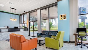 Un moderno vestíbulo de hotel con sofás de cuero, un mostrador de recepción y grandes ventanales que ofrecen vistas al exterior.