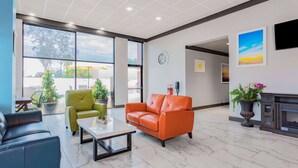 Un vestíbulo moderno con piso de mármol, sofás de cuero, una mesa de centro y ventanas amplias que ofrecen vistas al exterior.