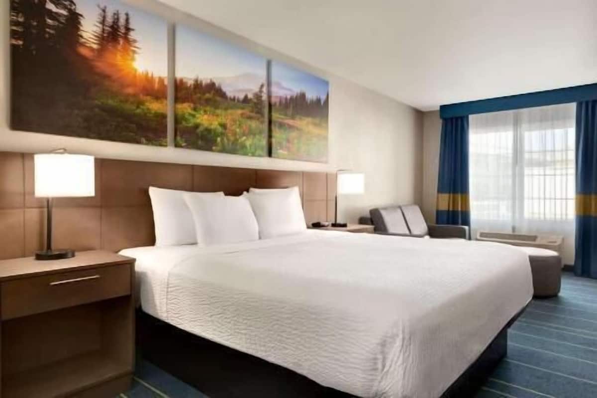 A hotel room with a large bed, two bedside tables, a desk, and a chair.