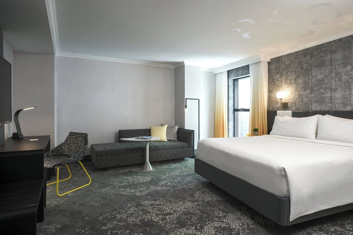 Una habitación de hotel moderna con una cama grande, un sofá, un escritorio y una mesita.