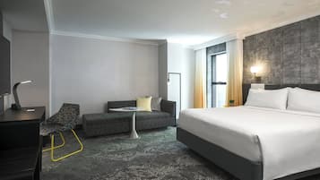 Una habitación de hotel moderna con una cama grande, un sofá, un escritorio y una mesita.