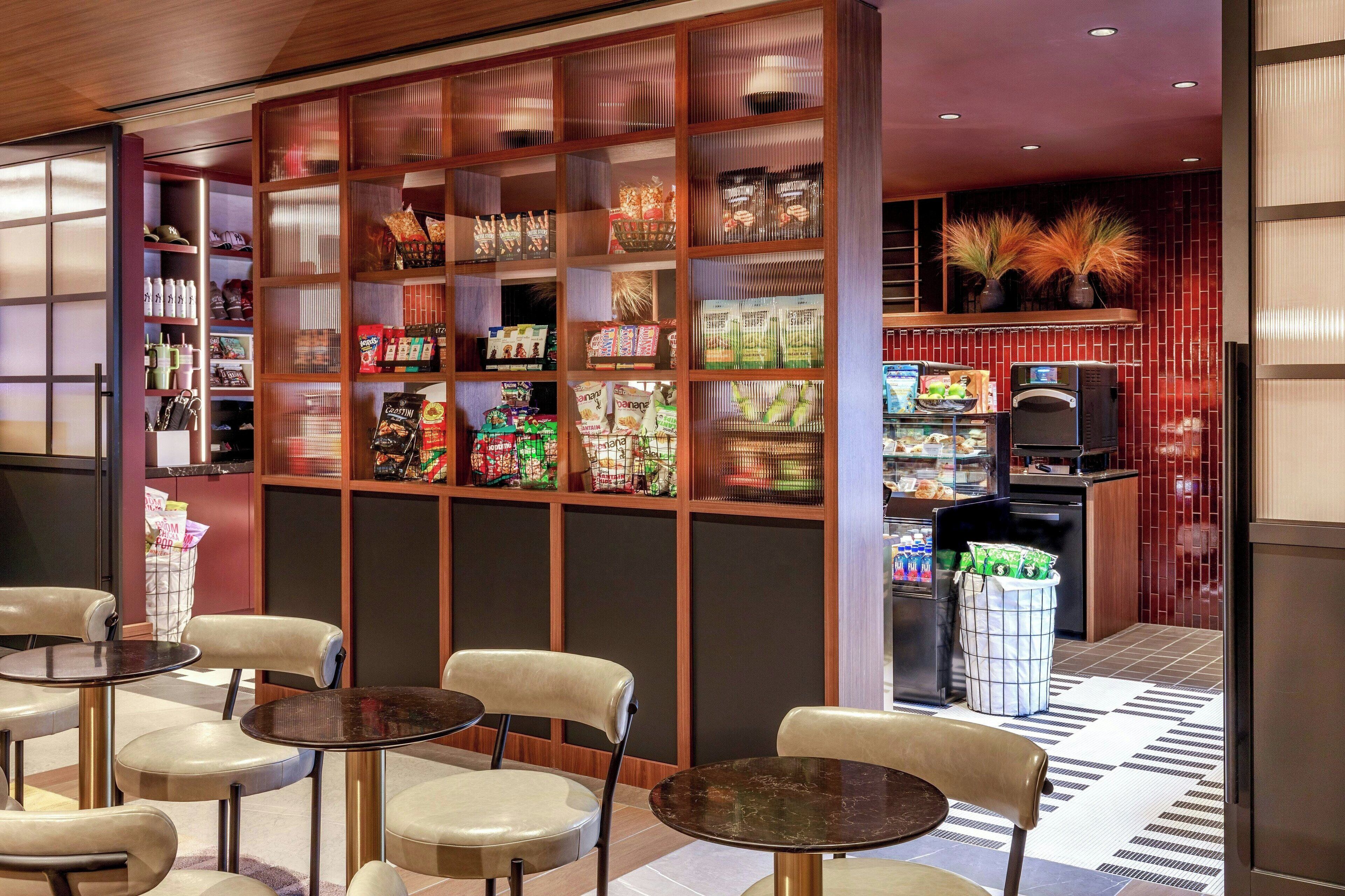 A restaurant with a variety of food items displayed on shelves, tables, and chairs for seating.