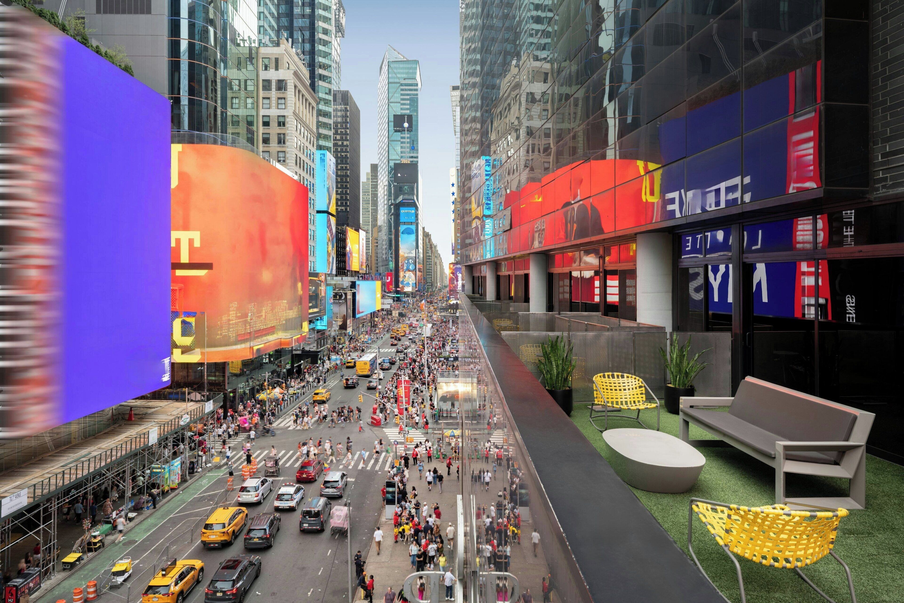 A busy urban street with tall buildings and a pedestrian walkway.