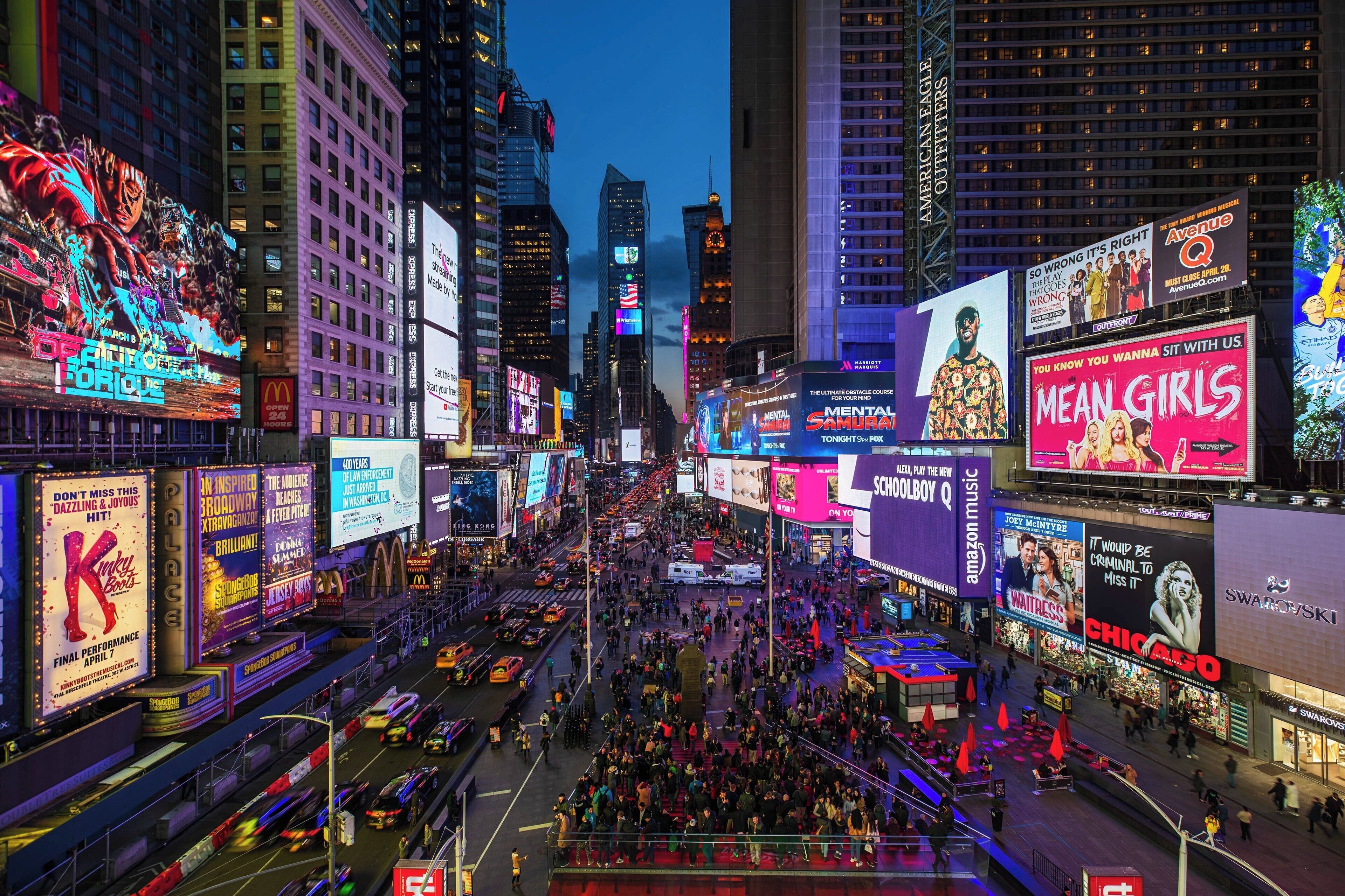 A busy urban street scene with numerous billboards and advertisements.