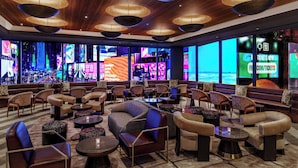 A spacious lounge area with comfortable seating, large windows, and a modern ceiling design. - Renaissance New York Times Square Hotel by Marriott (New York)