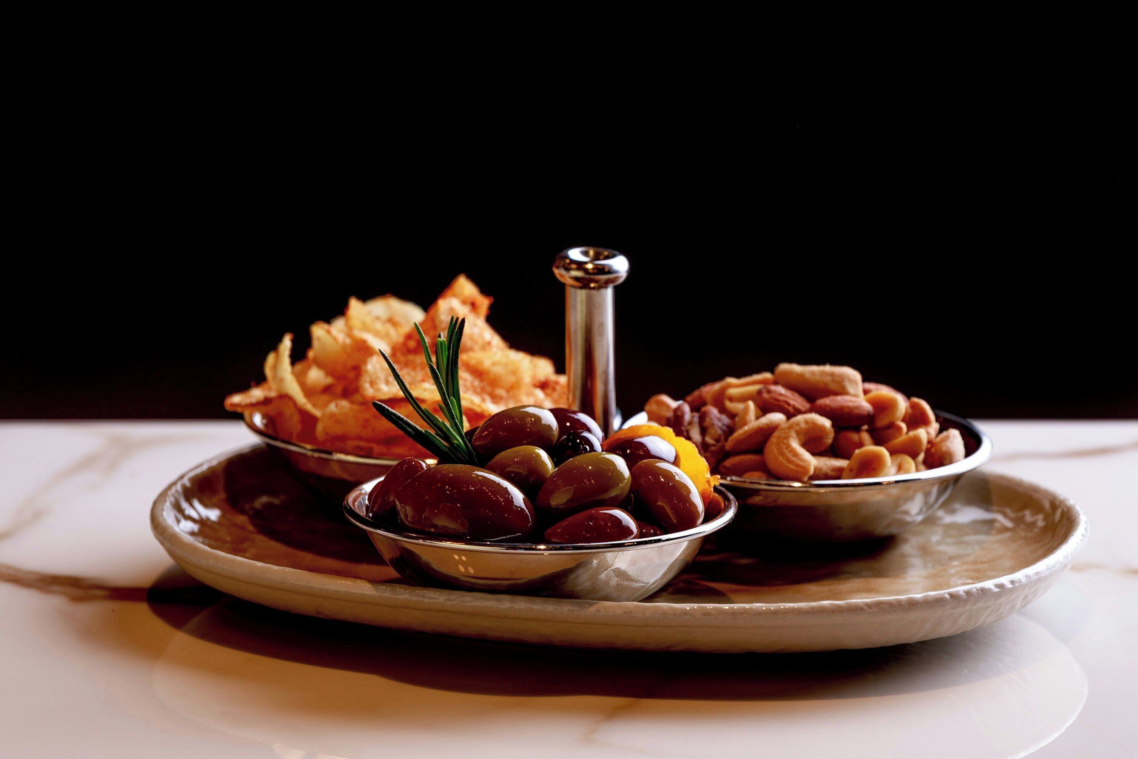 A plate with olives, almonds, and a sprig of rosemary.