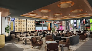 Ein stilvoller Lounge-Bereich mit Sofas, Sesseln und Tischen, mit großen Fenstern und Blick auf die Stadt.