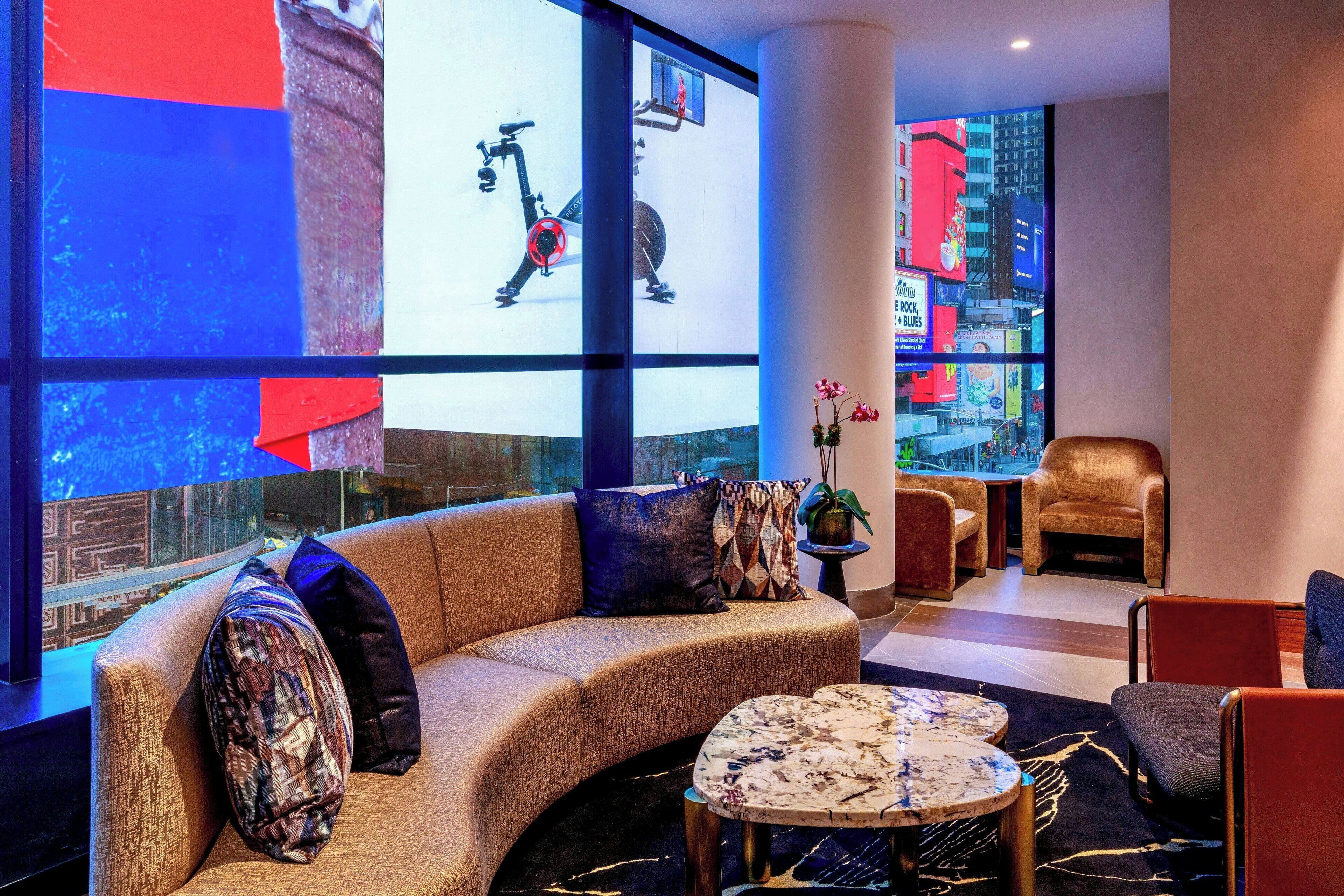 A modern hotel lobby with a curved sofa, armchairs, and a coffee table.