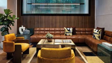 A modern living room with a brown leather sofa, a coffee table, and a large window with vertical blinds.
