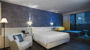 Ein modernes Hotelzimmer mit einem großen Bett, einer Sitzecke mit Blick und einem Schreibtisch mit Lampe.