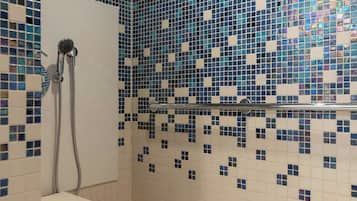 Un baño con paredes de mosaicos y una zona de ducha.
