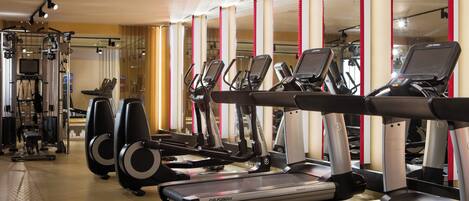 Un gimnasio con cintas de correr, elípticas y máquinas de pesas.